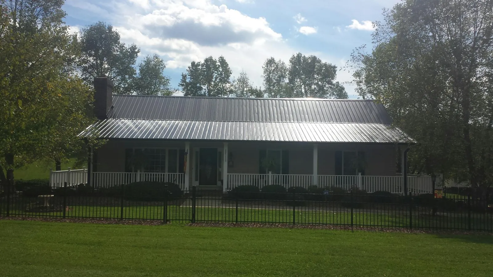 Gray metal roof on a brick ranch with a full width front porch — Gutter Guard Installation work by our crew in Unadilla